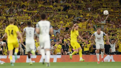 جمهور متحمس لفريق بودو/غليمت يحمل لافتات صفراء خلال مباراة نصف النهائي ضد توتنهام، مع التركيز على الأجواء الحماسية في الملعب.