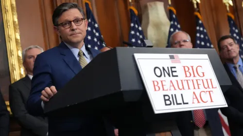 رجل يرتدي بدلة زرقاء يقف أمام منصة تحمل لافتة "مشروع قانون واحد كبير وجميل"، مع وجود مسؤولين آخرين خلفه، في مؤتمر صحفي حول التخفيضات الضريبية.