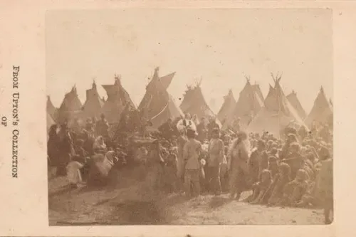 مجموعة من الأشخاص يجلسون أمام خيام تقليدية، مع وجود شخصيات بارزة في المقدمة، تعكس تاريخ الشعوب الأصلية في أمريكا.