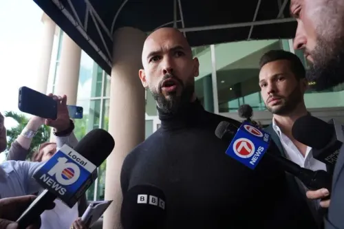 أندرو تيت يتحدث إلى الصحفيين خارج المحكمة، محاطًا بعدد من المراسلين، في سياق قضايا قانونية تتعلق بالتحرش والاتجار بالبشر.