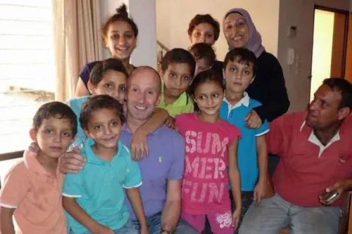 مجموعة من الأطفال والبالغين يجلسون معًا في غرفة، مبتسمين ويظهرون روح العائلة والتواصل، مما يعكس ذكريات الطفولة في غزة.