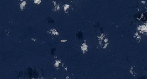 سفينة عسكرية صغيرة تظهر في مياه البحر الكاريبي، محاطة بغيوم، في سياق التوترات العسكرية بين فنزويلا والولايات المتحدة.