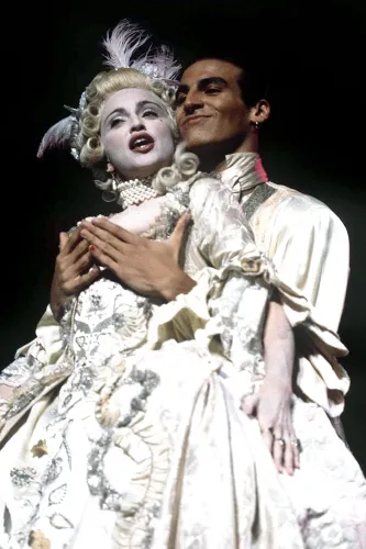 مشهد من عرض موسيقي يجسد ماري أنطوانيت، حيث يرتدي شخصان أزياء تاريخية فاخرة، مع تسريحات شعر متقنة، يعبران عن الفخامة والدراما.