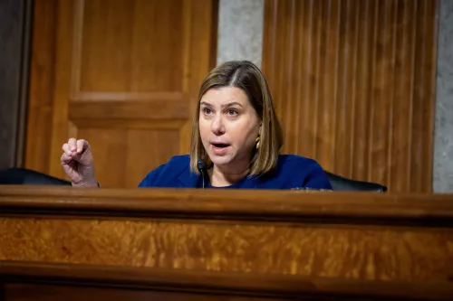 نائبة تتحدث خلال جلسة في قاعة بلدية، تواجه انتقادات حادة بشأن سياسات الهجرة والإنفاق الحكومي، وسط تفاعل متوتر من الجمهور.