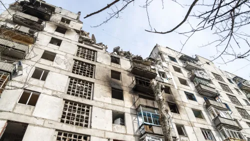مبنى سكني مدمر في أوكرانيا، يظهر آثار الحرب من خلال الشقوق والدمار في الواجهة، مما يعكس الصراع المستمر في المنطقة.