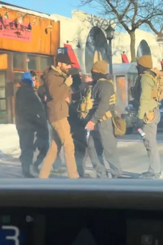 مجموعة من الأشخاص يرتدون ملابس عسكرية يتجمعون في منطقة حضرية، مع مشاهد من خلفية تشير إلى نشاطات أمنية.