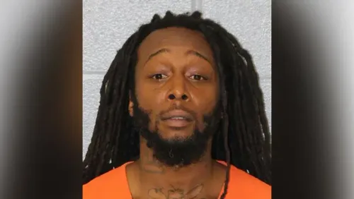 صورة لرجل ذو شعر مجعد طويل يرتدي سترة برتقالية، يظهر تعبيره الجاد. تم اعتقاله بتهمة القتل في حادثة طعن.