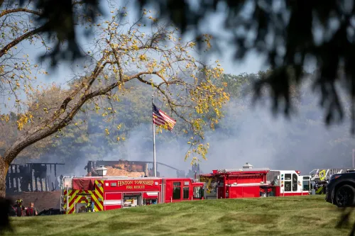 سيارة إطفاء حمراء تتواجد بالقرب من كنيسة صغيرة مشتعلة في بلدة غراند بلانك بولاية ميشيغان، مع تصاعد الدخان في الأجواء.