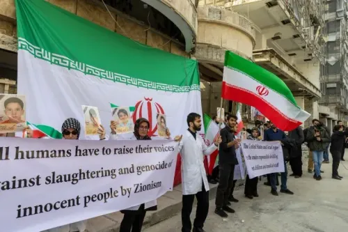 محتجون يحملون لافتات وشعارات أمام مبنى في إيران، مع أعلام وطنية، تعبيرًا عن استنكارهم للهجمات على المنشآت الطبية.