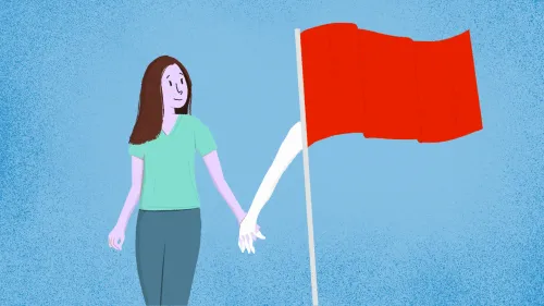 امرأة شابة تحمل يد شريكها، بينما تظهر خلفهما علم أحمر، مما يرمز إلى علامات الإنذار المبكر في العلاقات العاطفية.