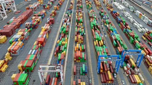 صورة لميناء يحتوي على حاويات شحن ملونة مرتبة بشكل منظم، تعكس تأثير التعريفات الجمركية على الاقتصاد الأمريكي.