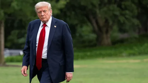 ترامب يسير في حديقة مع تعبير جاد، مرتديًا بدلة سوداء وقميصًا أبيض، ويعكس تأثير سياسته التجارية على الأسواق.