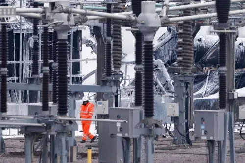 عامل يرتدي زي السلامة البرتقالي يتجول في محطة كهربائية فرعية متضررة بعد حريق، مما أثر على عمليات مطار هيثرو.