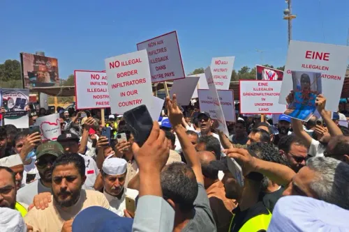 تجمع حشود من الليبيين أمام المفوضية السامية للأمم المتحدة للاجئين في طرابلس، حاملين لافتات تعبر عن رفضهم للمهاجرين غير الموثقين.