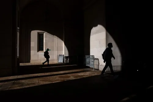 ظل شخصين يمشيان في ممر مظلم بمتحف سميثسونيان، مما يعكس تأثير الإغلاق الحكومي على المتعاقدين مع الحكومة.