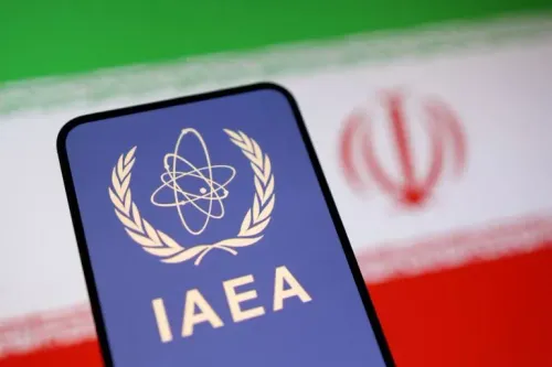 شعار الوكالة الدولية للطاقة الذرية (IAEA) أمام علم إيران، يرمز إلى التوترات حول البرنامج النووي الإيراني وعمليات التفتيش المطلوبة.