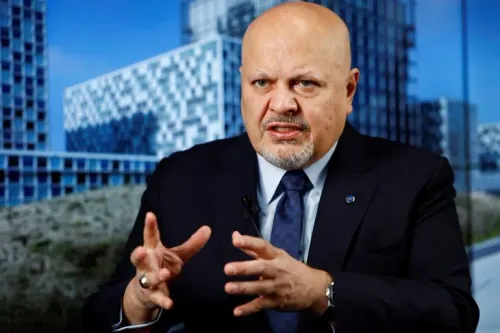 كريم خان، المدّعي العام للمحكمة الجنائية الدولية، يتحدث بجدية حول قضايا سوء السلوك الجنسي، وسط خلفية من المباني الحديثة.