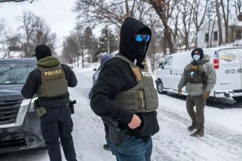 عناصر من الشرطة يرتدون سترات واقية في منطقة ثلجية بمينيسوتا، خلال عمليات اعتقال متعلقة بالهجرة، وسط توترات متزايدة.