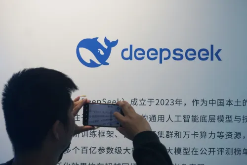شخص يلتقط صورة بشاشة تعرض شعار DeepSeek ونص صيني، مع التركيز على تطور الذكاء الاصطناعي الصيني وتنافسه مع النماذج الأمريكية.