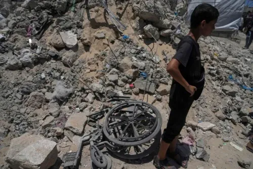 طفل يقف بجانب عربة معطلة وسط أنقاض في غزة، مما يعكس آثار الحرب المدمرة والأوضاع الإنسانية الصعبة.