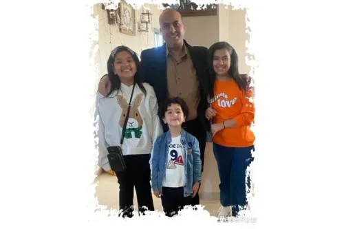 عائلة تتكون من أب وثلاثة أطفال في منزلهم، يعبرون عن الحب والترابط وسط ظروف صعبة بسبب النزاع في غزة.