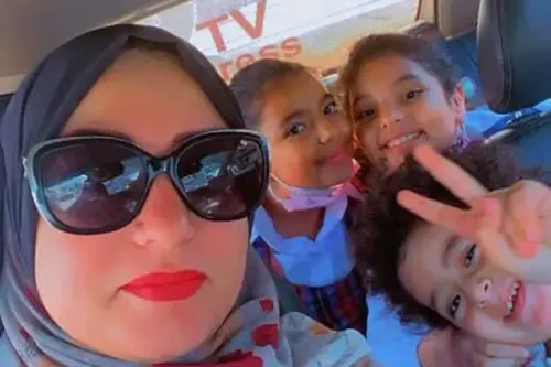 امرأة ترتدي حجابًا مع ثلاثة أطفال في سيارة، يعبرون عن الفرح. تعكس الصورة لحظات عائلية دافئة رغم الظروف الصعبة في غزة.