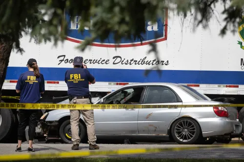 عملاء من مكتب التحقيقات الفيدرالي يفحصون موقع حادث حيث تم اتهام امرأة بصدم سيارة دورية. تظهر السيارة المتضررة خلف شريط الشرطة.