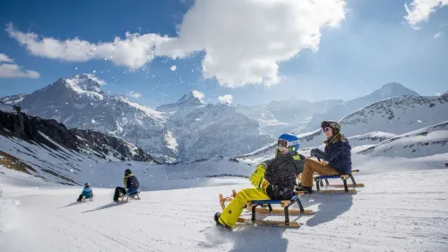 مجموعة من الأشخاص يتزلجون على زلاجات خشبية في جبال الألب السويسرية، محاطين بالثلوج والمناظر الجبلية الخلابة.