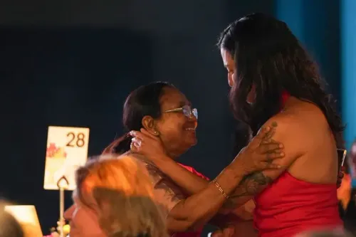 احتفال مؤثر بين امرأتين، إحداهما ترتدي فستانًا أحمر، تعبر عن الفرح بعد فوز بانو مشتاق وديبا بهاسثي بجائزة البوكر الدولية.