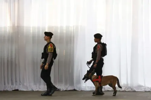 رجال شرطة إندونيسيون يسيرون مع كلب بوليسي، أثناء عملية مكافحة الاتجار بالبشر، خلف ستارة بيضاء، في إطار تحقيق في اختطاف الأطفال.