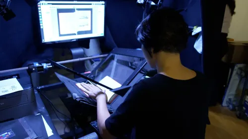 امرأة تعمل على مسح كتاب في مكتبة أرشيف الإنترنت، حيث تُستخدم تكنولوجيا حديثة لحفظ المحتوى الرقمي.