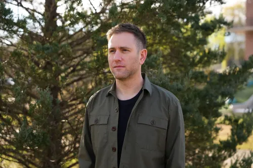 براين جولدستون، مؤلف كتاب "لا يوجد مكان لنا"، يقف أمام أشجار خضراء، معبرًا عن قضايا التشرد في أمريكا.