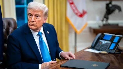 ترامب يجلس في المكتب البيضاوي، مرتديًا بدلة زرقاء وقميص أبيض، مع نظرة جدية، محاطًا بأدوات مكتبية.