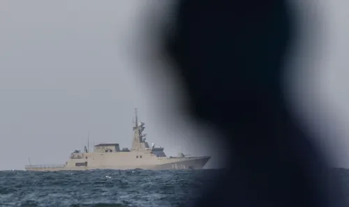 سفينة عسكرية تبحر في المياه، مع وجود ظل إنسان في المقدمة، تعكس حالة التوتر والقلق في فنزويلا.