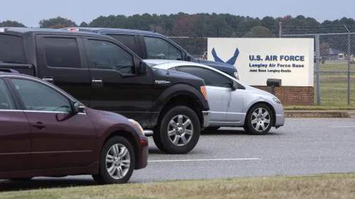 سيارات متوقفة أمام قاعدة لانغلي الجوية، مع لافتة تحمل شعار القوات الجوية الأمريكية، تعكس الأجواء المحيطة بموقع الحادث المأساوي.
