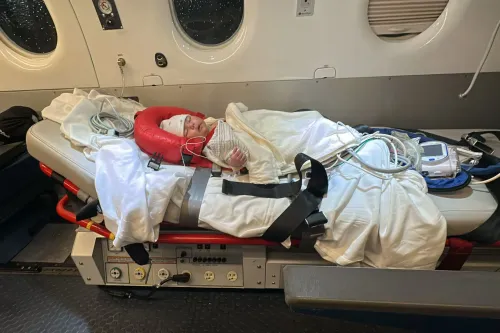طفلة صغيرة ترقد على سرير طبي داخل طائرة إسعاف، محاطة بأسلاك طبية وأجهزة مراقبة، تعاني من أعراض تسمم غذائي.