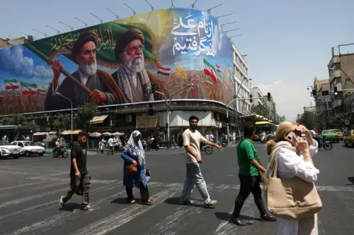 لوحة جدارية كبيرة في طهران تظهر شخصيات تاريخية إيرانية، مع أشخاص يعبرون الشارع. تعكس الصورة التوترات السياسية الحالية وتاريخ إيران.