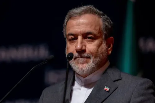 عباس عراقجي، وزير الخارجية الإيراني، يتحدث بجدية خلال مؤتمر، مع خلفية رمزية تعبر عن التوترات النووية العالمية.