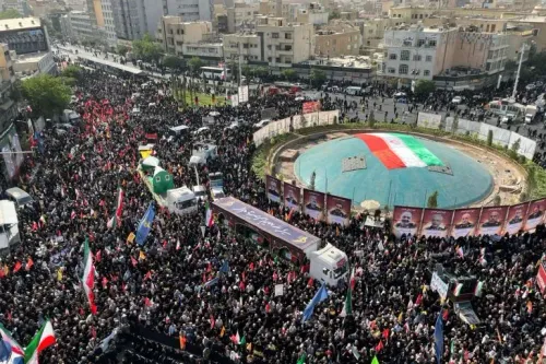 حشود ضخمة في طهران خلال مراسم تشييع قادة عسكريين وعلماء نوويين، حيث يحمل المشاركون الأعلام الإيرانية وصور القتلى.