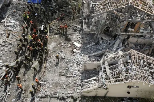 فرق الإنقاذ تعمل في موقع دمار كبير بعد الهجمات الصاروخية في إسرائيل، مع وجود أنقاض ومباني مدمرة في الخلفية.