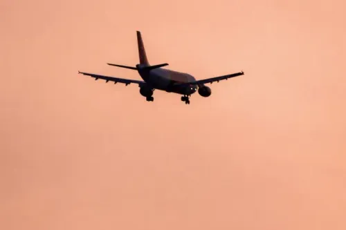 طائرة تحلق في السماء خلال غروب الشمس، تعكس التوترات الجيوسياسية في المنطقة بعد إغلاق المجال الجوي الإيراني.