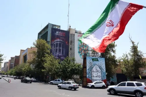علم إيران يرفرف فوق شارع في طهران وسط توترات تصاعدية بين الولايات المتحدة وإيران بعد ضربات عسكرية مستمرة.