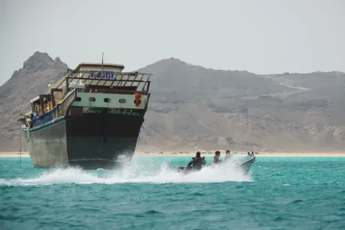 قارب سريع يقترب من سفينة شحن كبيرة في مياه باب المندب، مع خلفية جبلية، مما يبرز أهمية المنطقة كممر حيوي لتجارة الطاقة العالمية.