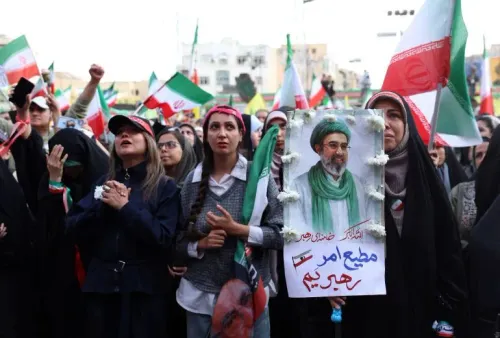 تجمع حشود من الإيرانيين في مظاهرة، يحملون لافتات وأعلام، مع التركيز على صورة قائد ديني، تعبيرًا عن دعمهم في ظل التوترات السياسية.