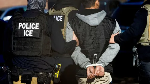 تظهر الصورة ضباط إنفاذ قوانين الهجرة وهم يعتقلون مهاجراً، مما يعكس تأثير الاتفاق بين مصلحة الضرائب ووزارة الأمن الداخلي على عمليات الترحيل.