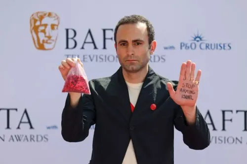 ممثل يحمل كيسًا من الحبوب الحمراء بيده اليسرى، ويظهر على يده اليمنى عبارة "أوقفوا تسليح إسرائيل"، في فعالية BAFTA.