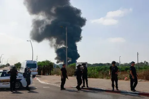 تصاعد دخان كثيف من موقع ضربة في هرتسيليا، بينما يتواجد أفراد من الشرطة الإسرائيلية في موقع الحادث.