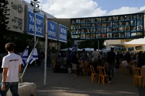 مظاهرة في تل أبيب لدعم الأسرى، حيث يظهر لافتات بأسماء الأسرى وصورهم، مع وجود حشد من الناس في الخلفية.