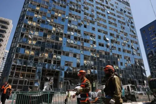 مبنى متضرر بشدة نتيجة الهجمات، مع نوافذ محطمة وأشخاص يرتدون زي الإنقاذ يتجولون في المنطقة.