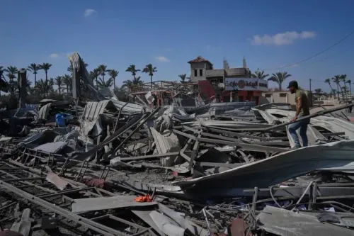 تظهر الصورة دمارًا واسعًا في دير البلح بقطاع غزة، مع شخص يتجول بين الأنقاض، مما يعكس آثار الهجمات الإسرائيلية على المدنيين.